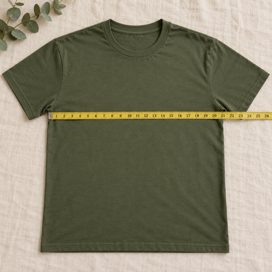 A tee laid flat with a tape measure across the chest, from one underarm seam to the other